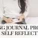 woman sits in pyjamas writing evening journal prompts in a notebook